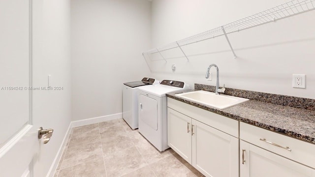 washroom with sink, cabinets, light tile floors, and washing machine and clothes dryer