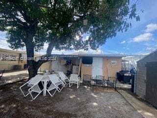 rear view of property featuring a storage unit and a patio