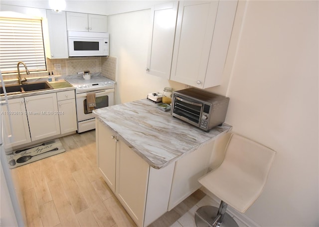 kitchen featuring white appliances, light wood-type flooring, backsplash, white cabinets, and sink