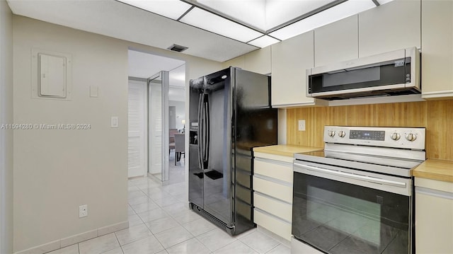 kitchen with light tile flooring, range with electric cooktop, and black fridge with ice dispenser