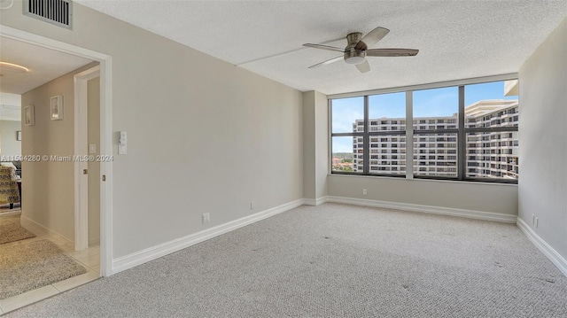 spare room featuring carpet, ceiling fan, and a textured ceiling