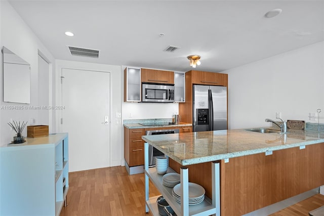 kitchen featuring stainless steel appliances, light stone counters, light hardwood / wood-style flooring, and kitchen peninsula