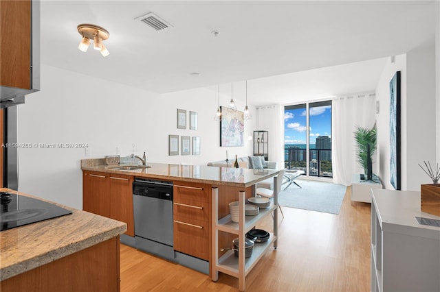 kitchen featuring light stone countertops, light wood-type flooring, stainless steel dishwasher, decorative light fixtures, and sink