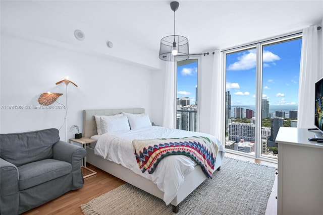 bedroom featuring expansive windows, hardwood / wood-style flooring, and access to exterior