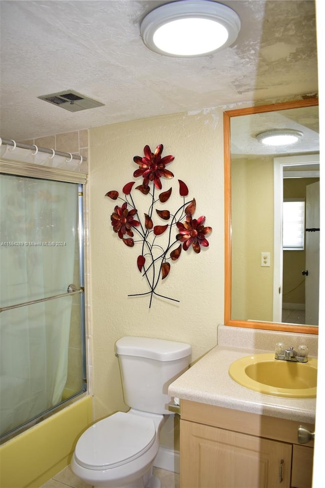 full bathroom featuring combined bath / shower with glass door, toilet, tile flooring, vanity, and a textured ceiling