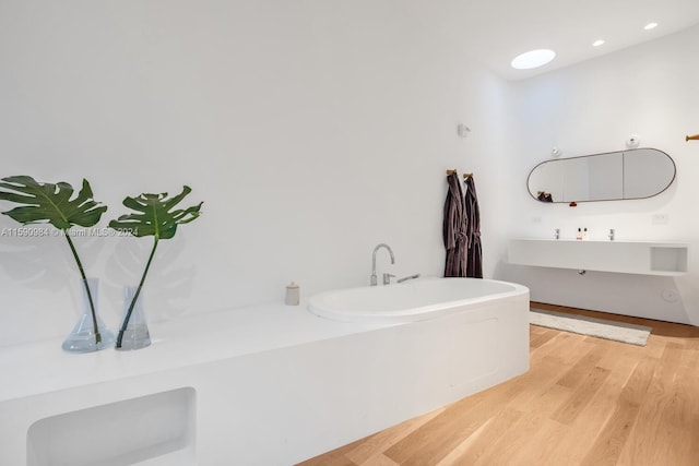 bathroom with a bath to relax in and hardwood / wood-style floors