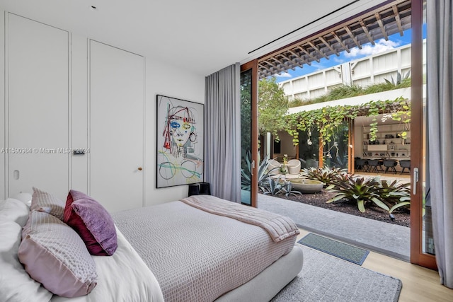 bedroom featuring hardwood / wood-style floors, a wall of windows, and access to outside