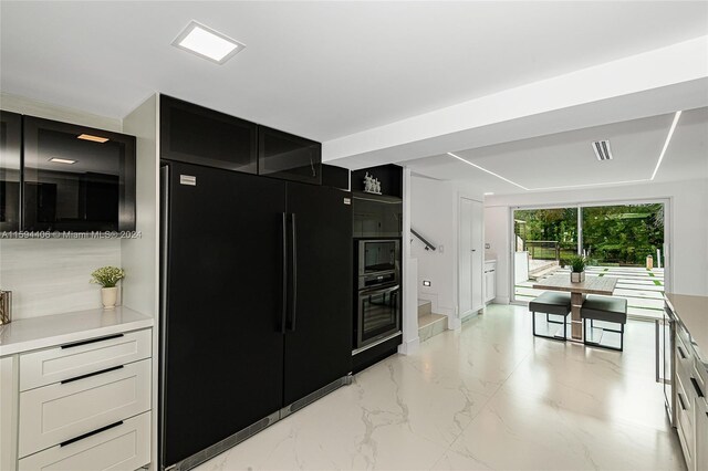 kitchen featuring white cabinets, light tile flooring, and black appliances