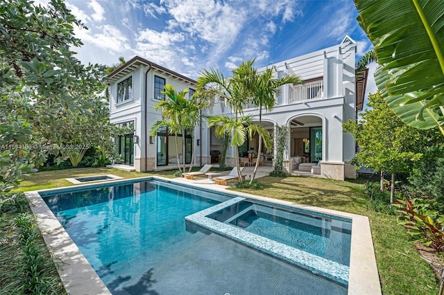 rear view of house featuring a balcony, a patio area, an outdoor pool, and an in ground hot tub