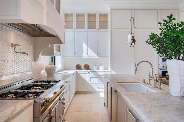 kitchen featuring custom range hood, glass insert cabinets, backsplash, and a sink