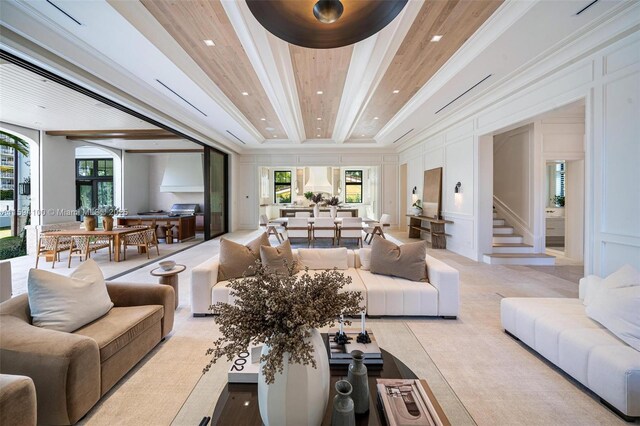 living room featuring crown molding, plenty of natural light, a decorative wall, and stairway