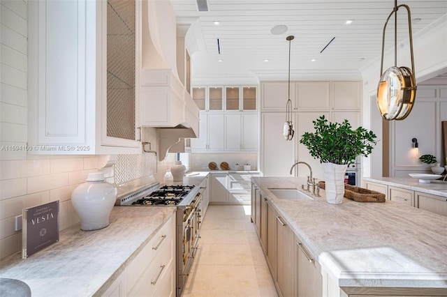 kitchen with decorative light fixtures, sink, decorative backsplash, high end stainless steel range, and custom range hood