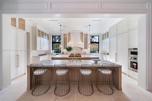 kitchen featuring premium range hood, a spacious island, white cabinetry, and hanging light fixtures