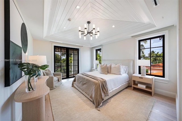 bedroom with access to outside, multiple windows, and a tray ceiling