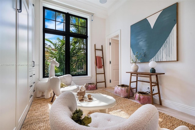 sitting room featuring ornamental molding, a wealth of natural light, baseboards, and wood finished floors