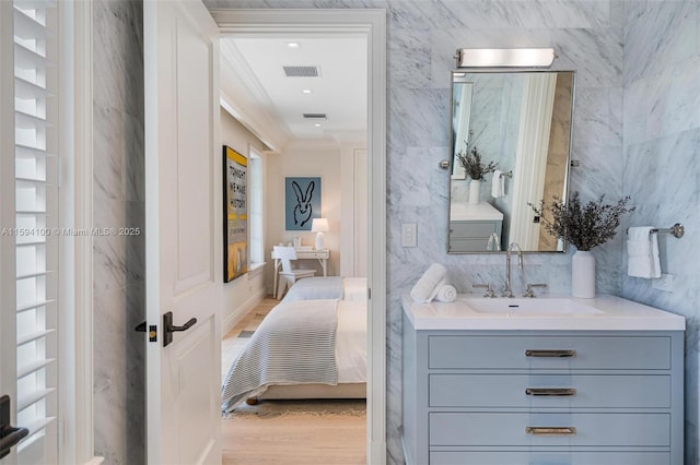 ensuite bathroom with ornamental molding, visible vents, tile walls, and wood finished floors