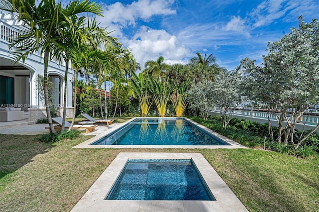 pool featuring a yard, a patio area, and an in ground hot tub