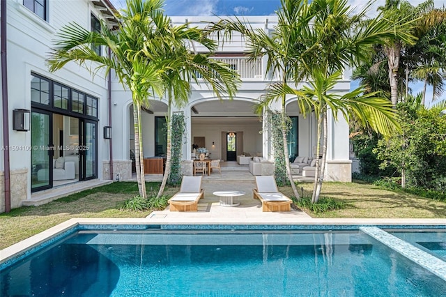 back of property with a balcony, a patio area, and a pool with connected hot tub