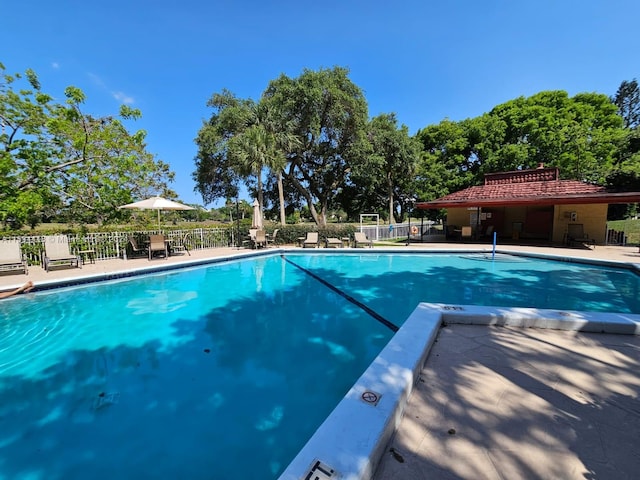 community pool with a patio and fence