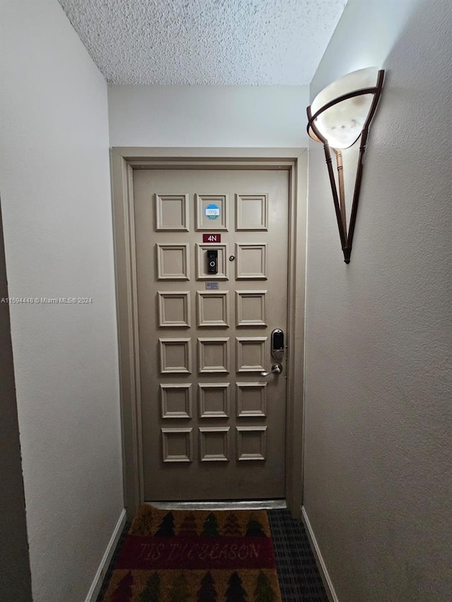 entryway with dark carpet and a textured ceiling