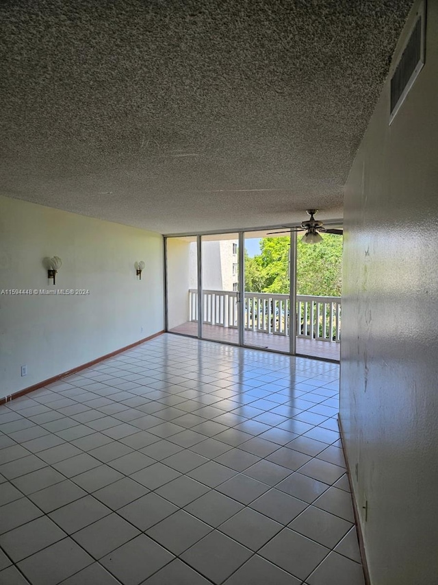 spare room with ceiling fan, a textured ceiling, light tile patterned floors, and expansive windows