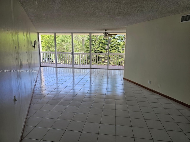 unfurnished room featuring expansive windows, a textured ceiling, light tile patterned floors, and ceiling fan