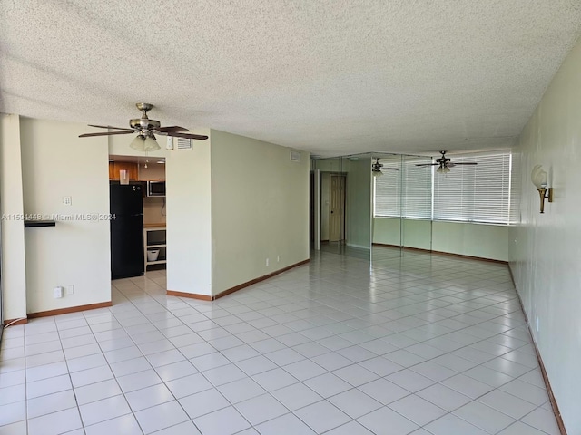 unfurnished room with ceiling fan, light tile patterned flooring, and a textured ceiling