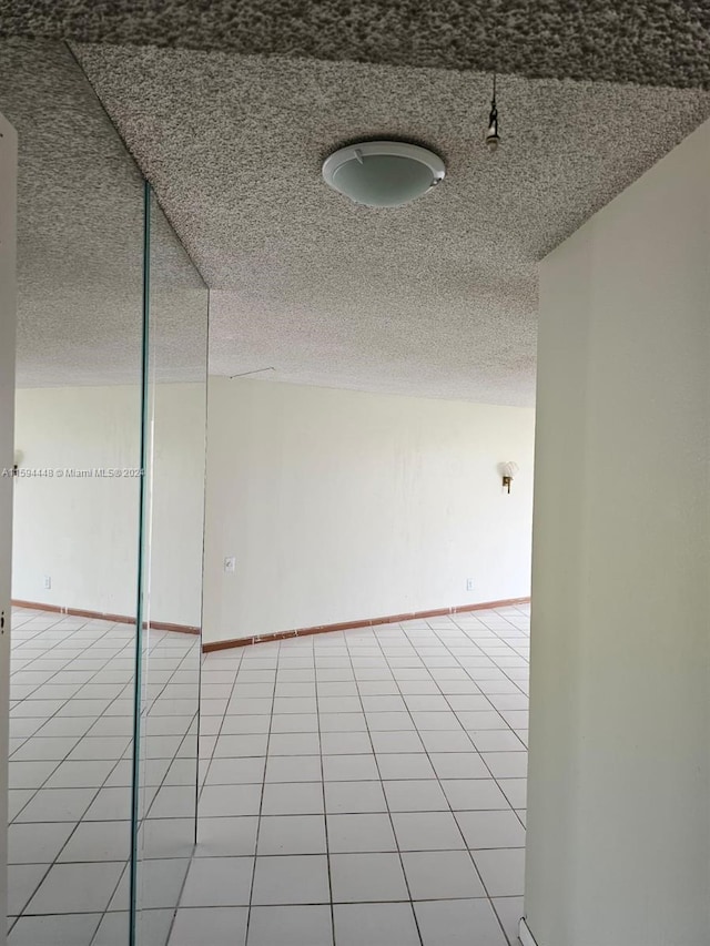 spare room with light tile patterned flooring and a textured ceiling