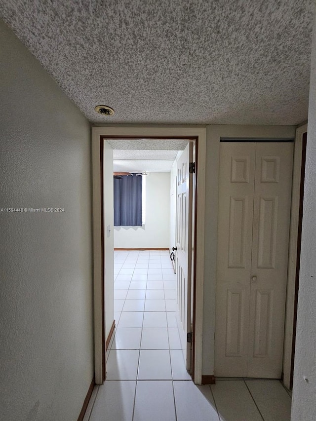 hallway featuring a textured ceiling and light tile patterned floors