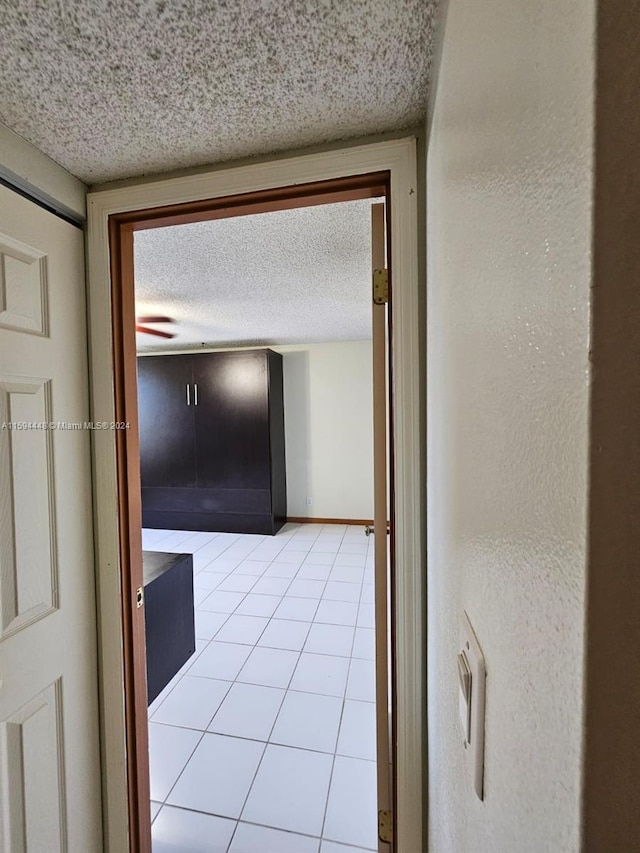 hallway with light tile patterned floors and a textured ceiling