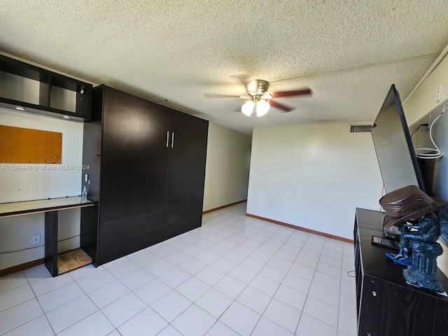 interior space featuring light tile patterned floors, a ceiling fan, visible vents, baseboards, and a textured ceiling