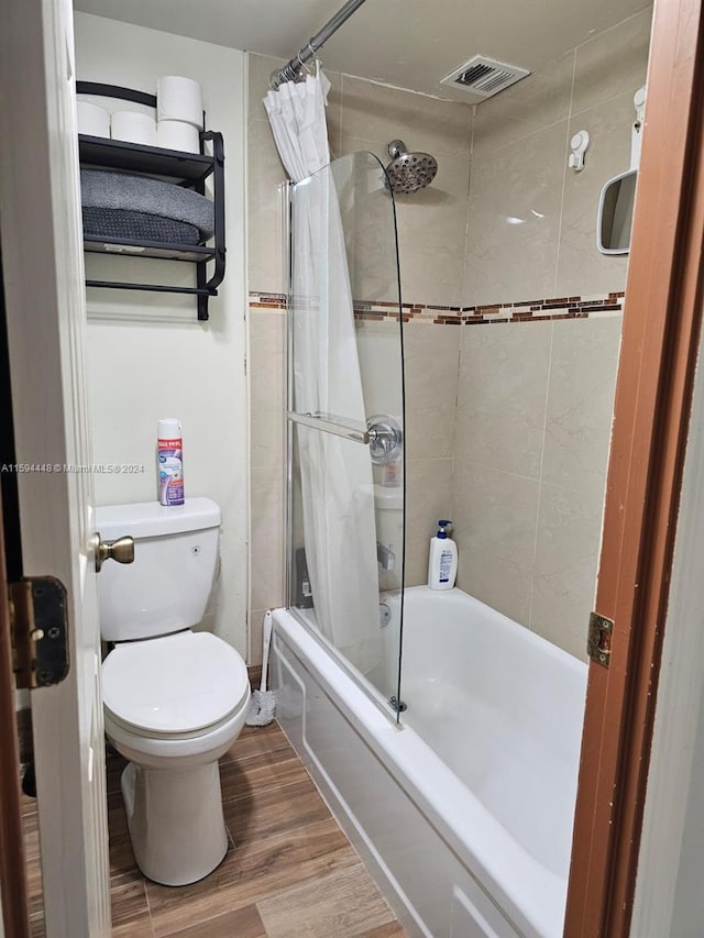 full bathroom featuring visible vents, shower / bathtub combination with curtain, wood finished floors, and toilet