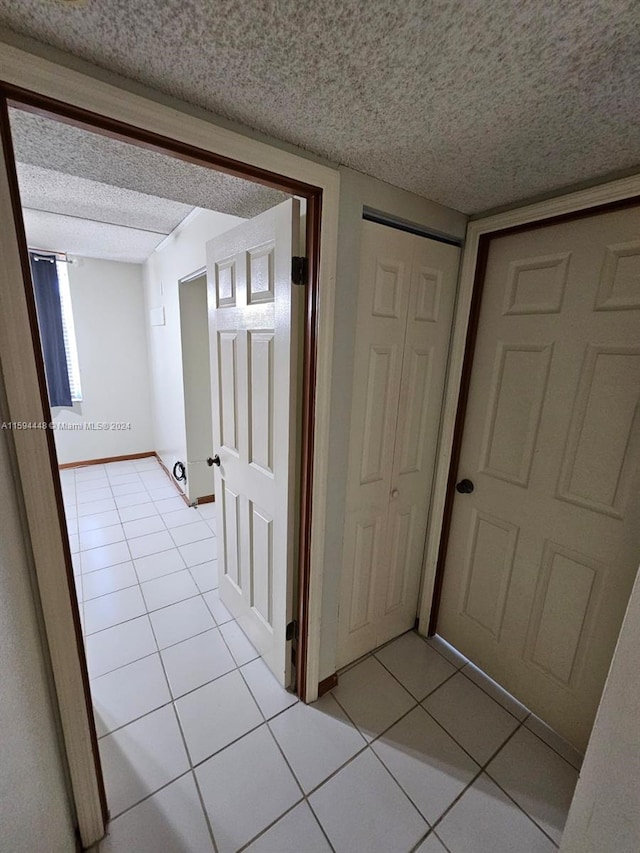 hall with a textured ceiling and light tile patterned floors