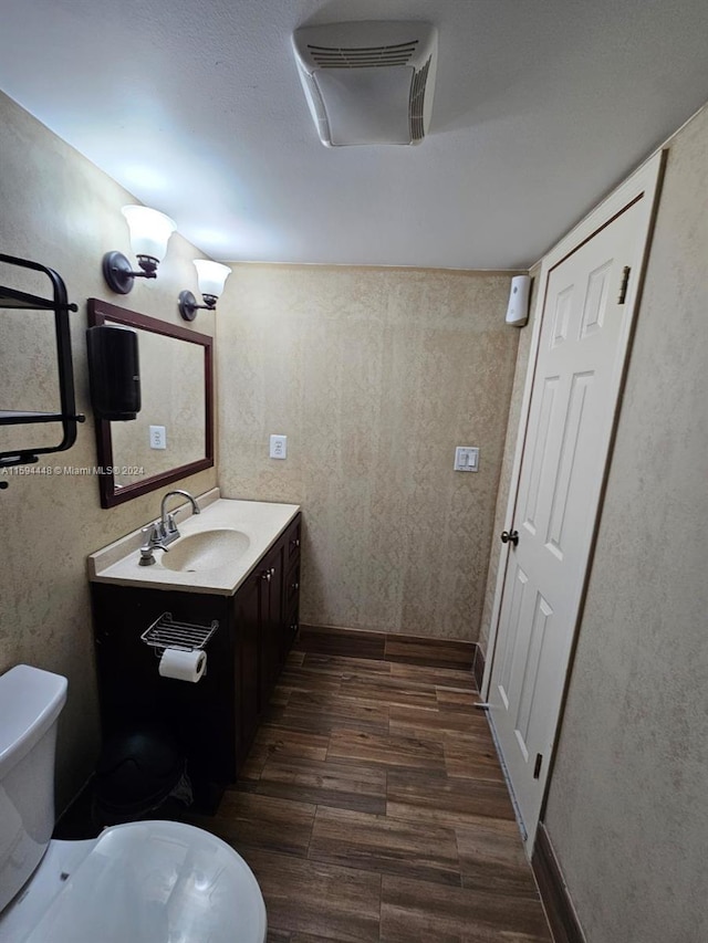 bathroom with toilet, vanity, and hardwood / wood-style floors