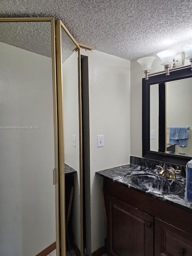 bathroom featuring a shower with shower door, vanity, and a textured ceiling