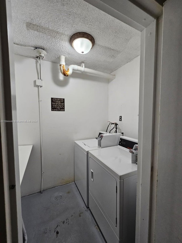 clothes washing area featuring washer and clothes dryer and a textured ceiling