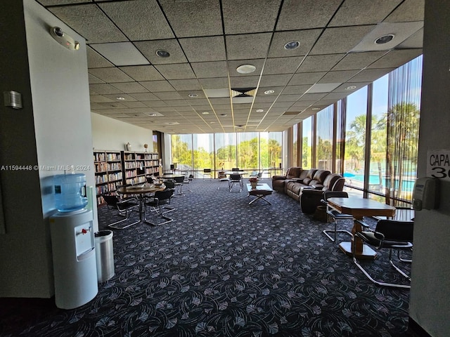 gym featuring dark colored carpet, a drop ceiling, and a wall of windows