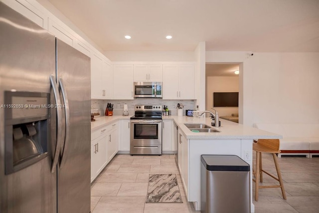 kitchen featuring kitchen peninsula, tasteful backsplash, stainless steel appliances, light tile floors, and sink