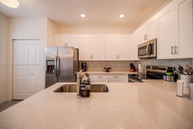 kitchen with light stone counters, stainless steel appliances, tasteful backsplash, white cabinets, and sink