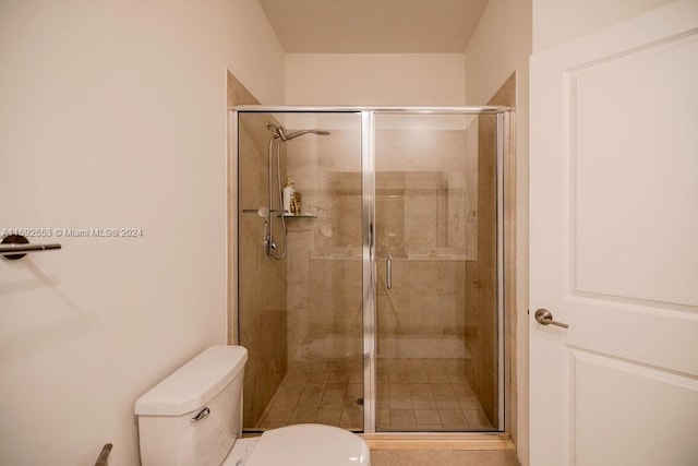 bathroom featuring a shower with shower door and toilet