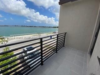 balcony featuring a view of the beach and a water view