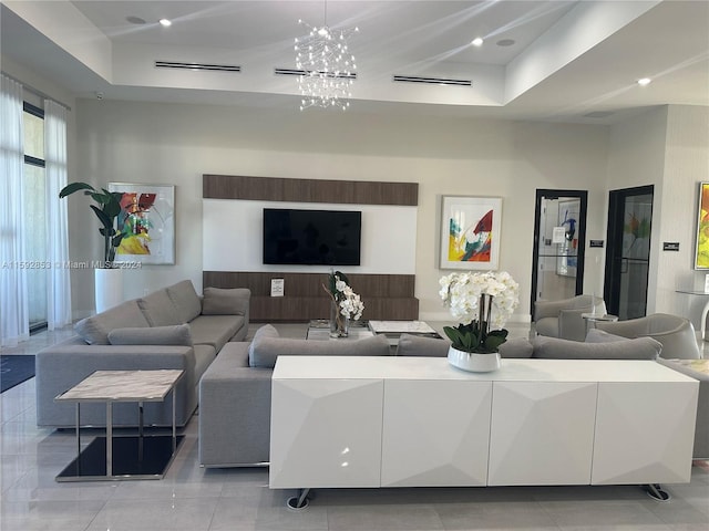 tiled living room featuring an inviting chandelier and a tray ceiling