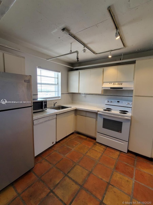 kitchen featuring sink, white appliances, dark tile floors, and rail lighting