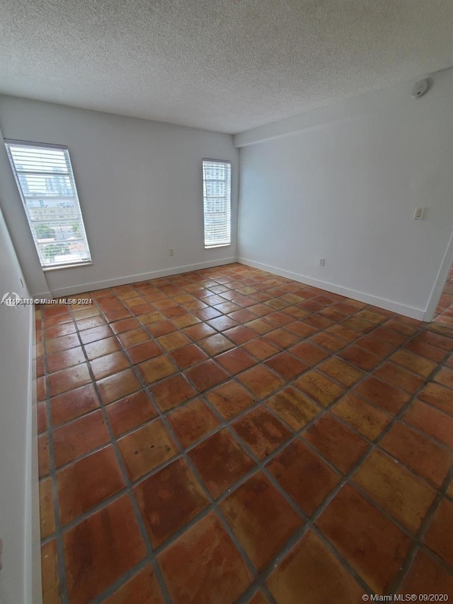 tiled empty room featuring a textured ceiling