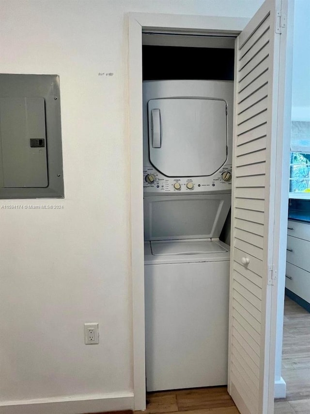 laundry room with stacked washer and clothes dryer, light hardwood / wood-style floors, and electric panel