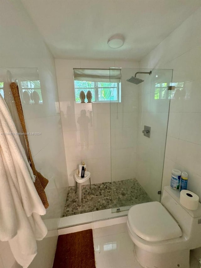 bathroom featuring toilet, tile patterned flooring, an enclosed shower, and tile walls