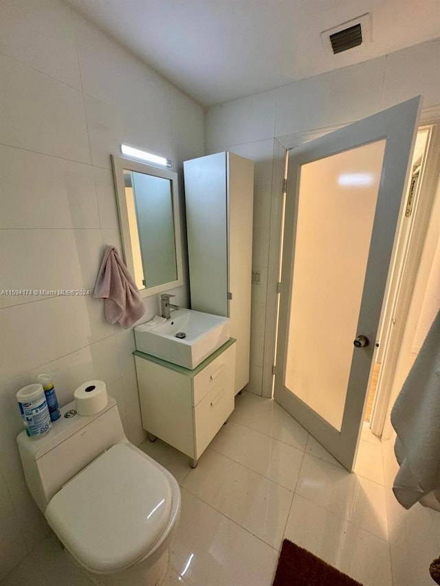 bathroom with vanity, toilet, tile patterned flooring, and tile walls