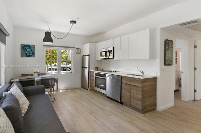 kitchen with decorative light fixtures, stainless steel appliances, light countertops, white cabinets, and modern cabinets