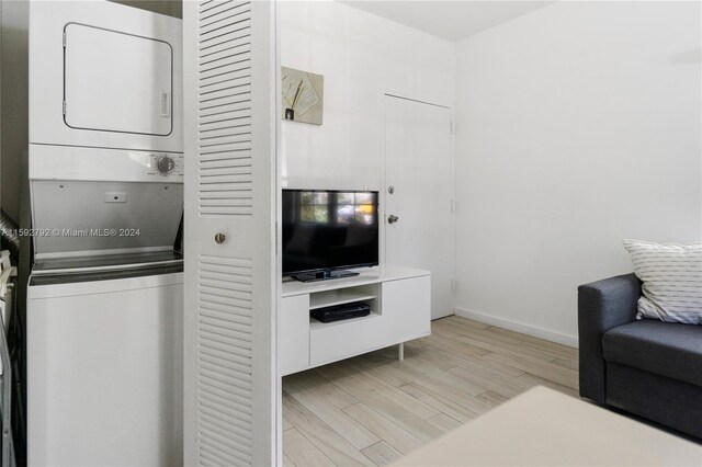 laundry area featuring stacked washer / drying machine and light hardwood / wood-style flooring