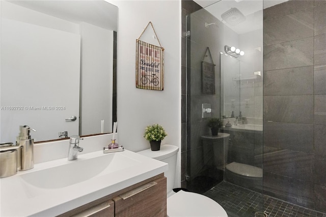 bathroom featuring vanity with extensive cabinet space, toilet, and a shower with door